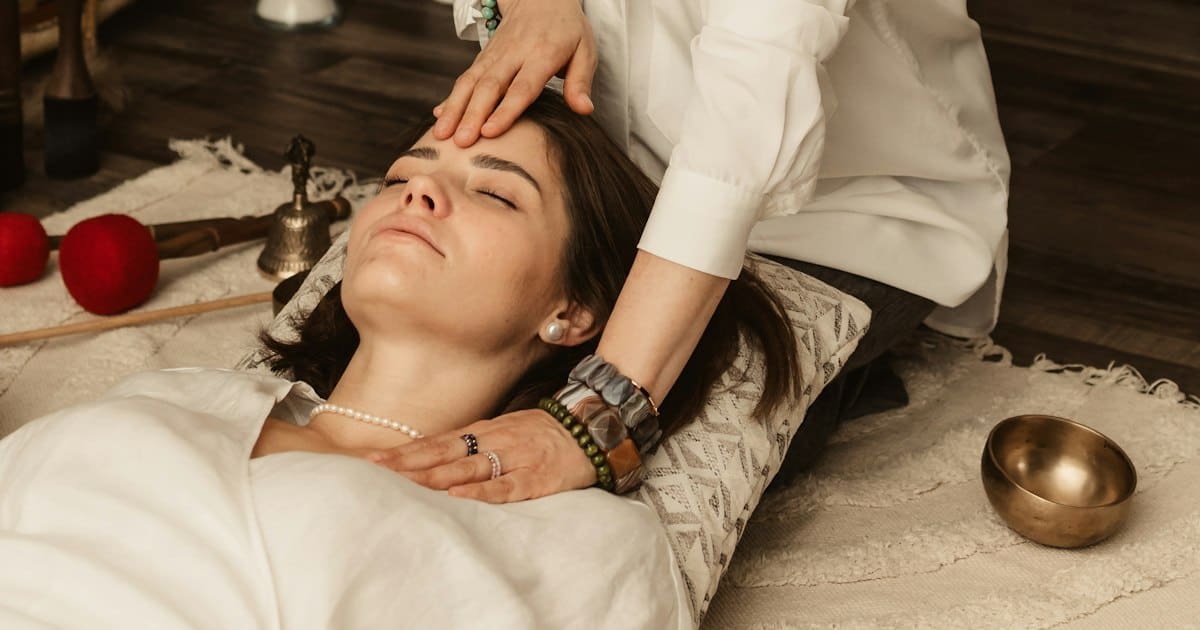 Sesión de Reiki con las manos de la terapeuta sobre la frente